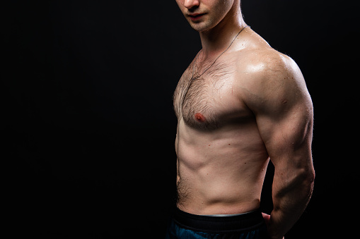 Man on black background keeps dumbbells pumped up in fitness bodybuilding biceps sport, arm muscular lifting heavy, person weightlifting. Young people fit hands behind your back, press tense beautiful body