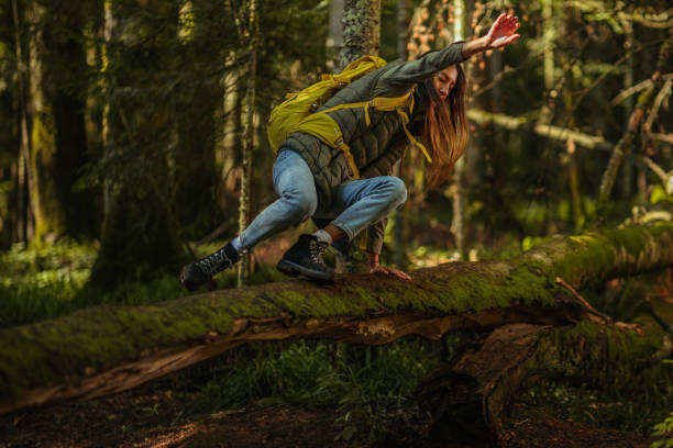 istock Young woman jumping over a log in the forest 1321022021