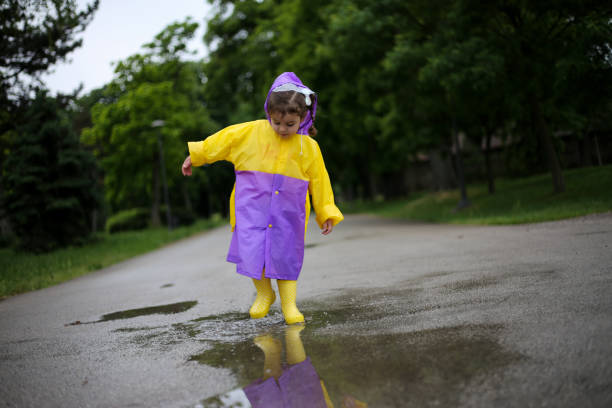 노란 부츠를 입은 아이가 웅덩이에서 점프합니다. 스톡 사진 - child looking messy urban scene 뉴스 사진 이미지