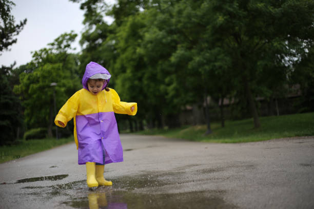 노란 부츠를 입은 아이가 웅덩이에서 점프합니다. 스톡 사진 - child looking messy urban scene 뉴스 사진 이미지