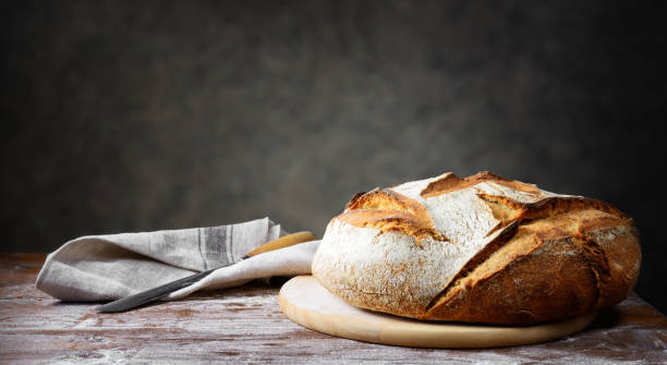 istock Traditional loaf of bread on rustic table with gray backdrop, space for text. 1321024061
