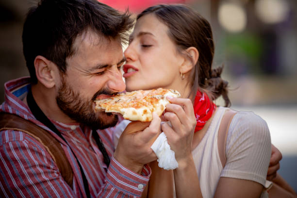 istock Happy couple sharing pizza on street 1321025818