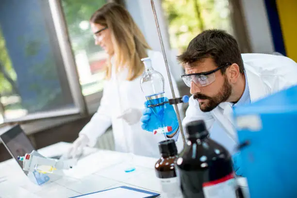 Photo of Researchers working with blue liquid at separatory funnel