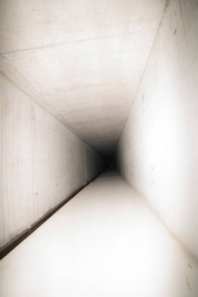 empty road through tunnel built for avalanche protection in the mountains, sun shining through and forming a pattern of light and shadow on the street