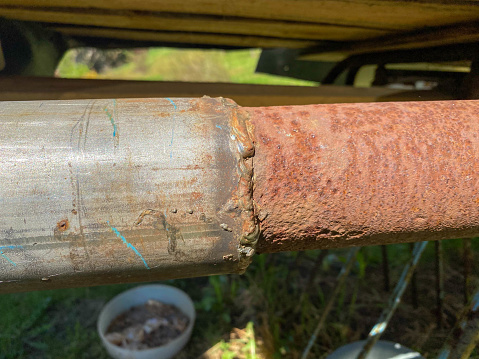 Weld joint between iron metal industrial old rusty pipe and new stainless steel pipe.