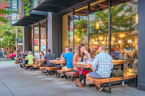 People dine on a restaurant patio in downtown Portland Oregon USA in the evening.