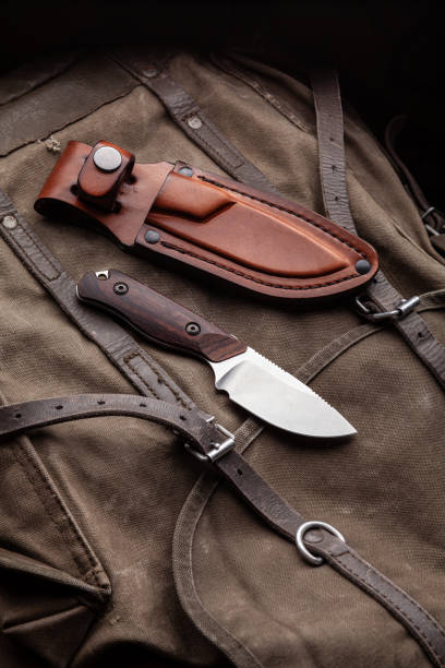 istock A hunting knife with a wooden handle and a leather case on a khaki canvas backpack. Weapons for self-defense and survival. 1321029686