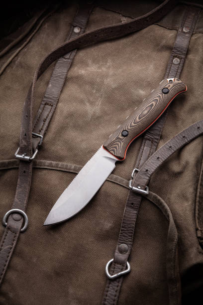 istock A hunting knife with a wooden handle on a khaki canvas backpack. Weapons for self-defense and survival. 1321029690
