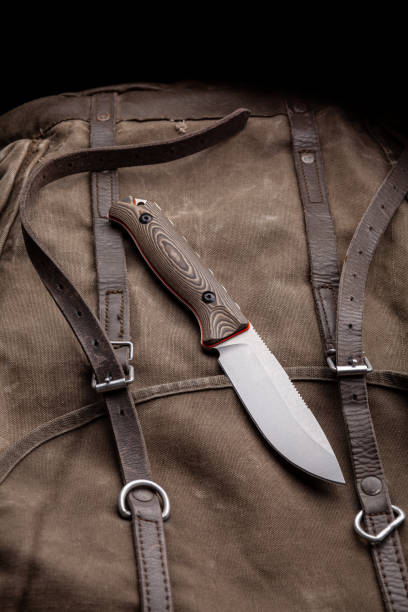 istock A hunting knife with a wooden handle on a khaki canvas backpack. Weapons for self-defense and survival. 1321029693
