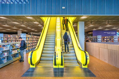 People use the escalator inside the Seattle Central Library in downtown Seattle Washington USA on a sunny day.