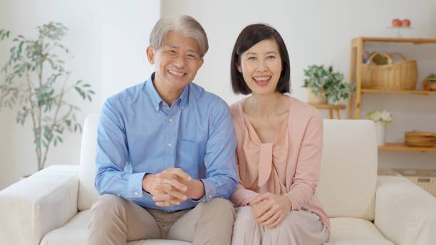 middle aged asian couple in the living room middle aged asian couple in the living room mid adult couple stock pictures, royalty-free photos & images