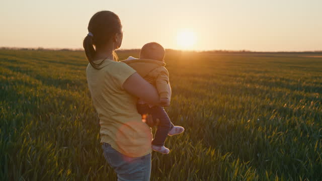 Farmer with baby in wheat field at sunset. Agricultural concepts.