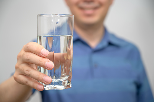 Middle-aged Asian man holding a glass of water.