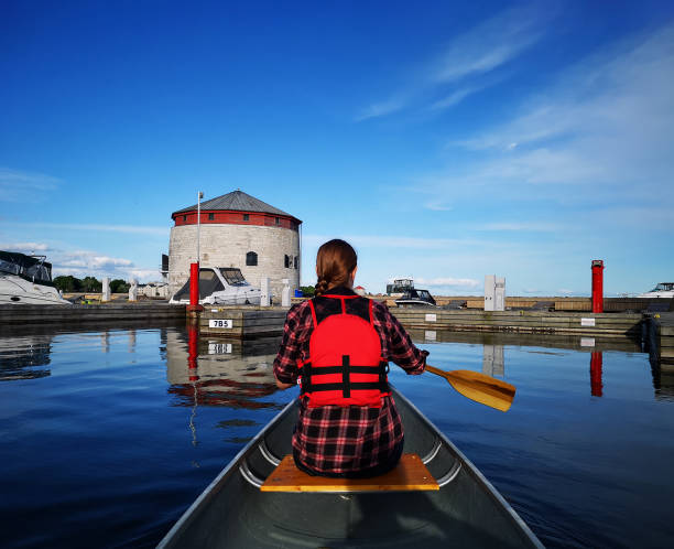 Canoeing in Kingston Ontario Canoe paddled by young woman, paddling in the harbour of Kingston, Ontario. Victoria Tower, one of Kingston's four Martello Towers, is in the background. Active lifestyle paddling stock photo, Kingston Canada. kingston ontario photos stock pictures, royalty-free photos & images