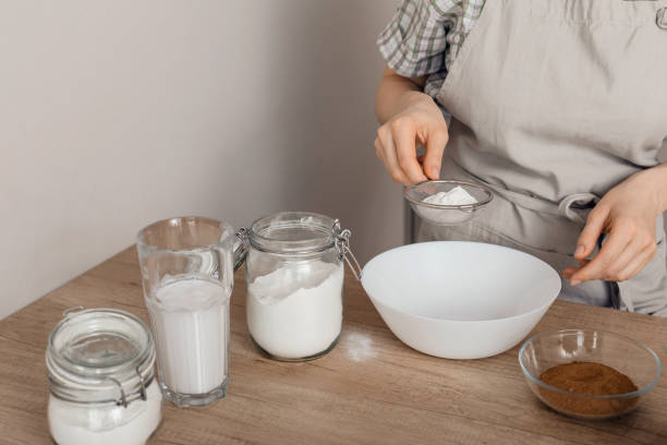 el proceso de elaboración de productos horneados sin gluten.  la harina de arroz se tamiza a través de un tamiz. el concepto de cocinar pasteles vegetarianos. - sieved fotografías e imágenes de stock