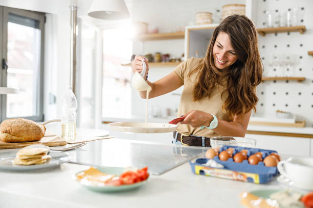 istock Happy woman preparing dough for pancakes in the kitchen. 1321071470