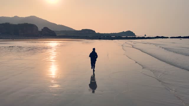 Young man running on beach in morning