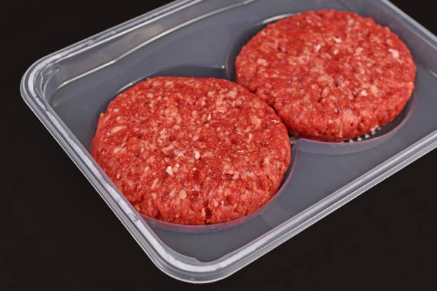 istock Round raw burger patties in package on dark background 1321073386