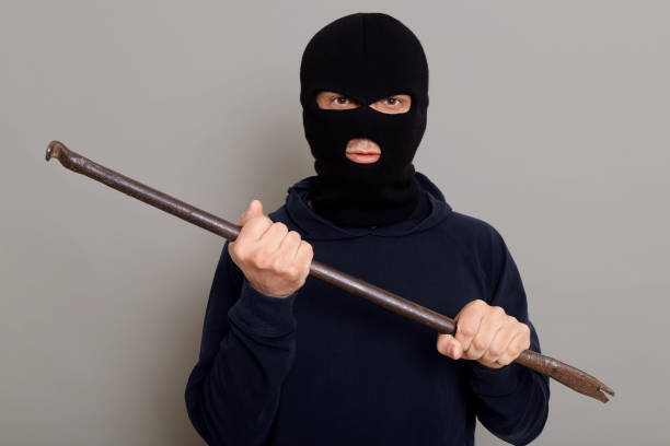 istock An evil insidious criminal thief man with an iron crowbar in his hands, is going to break down the door, rob an apartment, looks at camera with a sly and insidious expression on his face. 1321074581