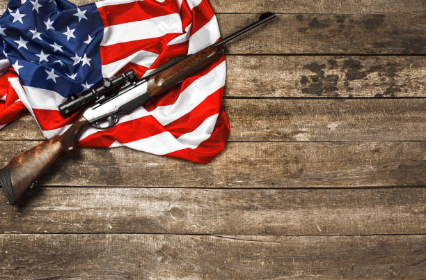 istock Automatic rifle on USA flag on wooden background 1321077287