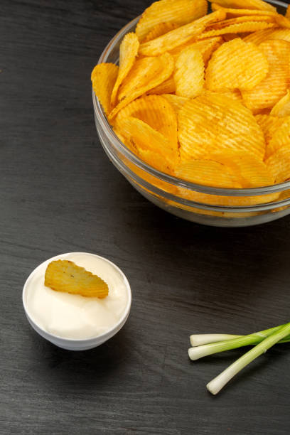istock Potato chips in bowl and sour cream and onion on black background 1321078767