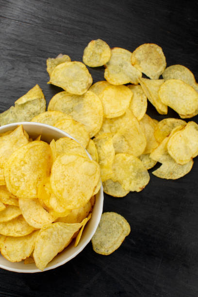 istock Potato chips in bowl on black background 1321078776