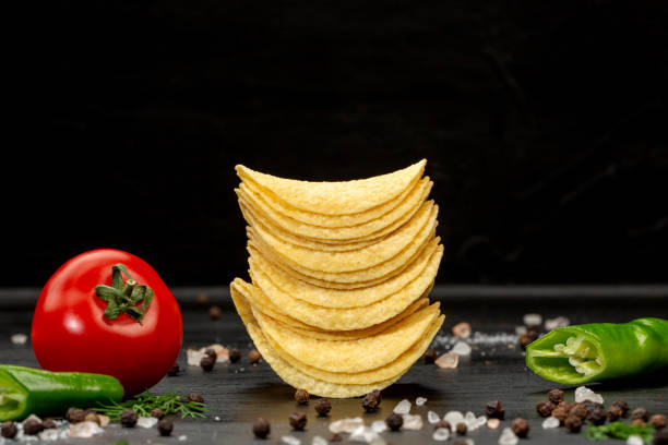 istock Potato chips and vegetables in composition on black background 1321079472