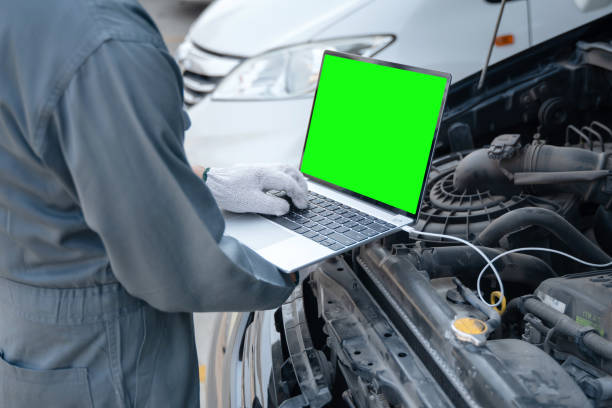 механик с помощью ноутбука для проверки сбора информации во время работы двиг�ателя автомобиля. обслуживание промышленных для ремонта двиг - chroma key flash стоковые фото и изображения
