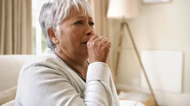 Photo of Shot of an elderly woman coughing into her hand