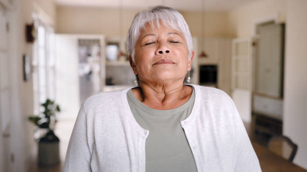 plan d’une femme âgée prenant une profonde respiration et profitant de l’air frais à la maison - exercice de respiration photos et images de collection