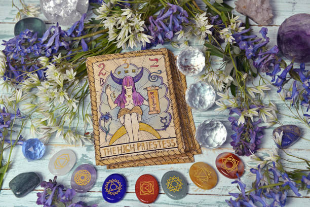 Still life with High Priestess card of the old tarot deck on witch altar table with chakra crystals and flowers. Still life with High Priestess card of the old tarot deck on witch altar table with chakra crystals and flowers. Esoteric, gothic and occult background, Halloween mystic and wicca concept. crystal altar stock pictures, royalty-free photos & images