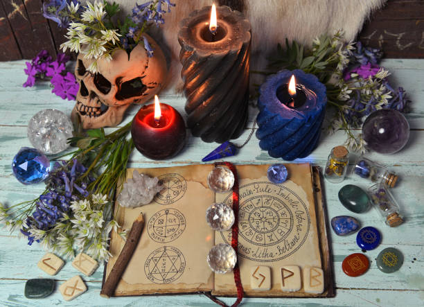 istock Still life with open witch book, crystal, burning candles and flowers on altar table. 1321085818