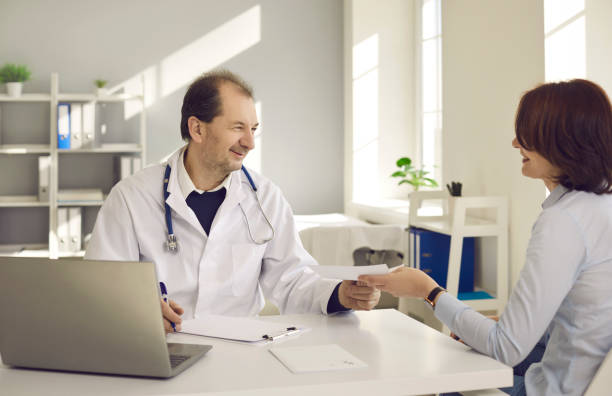 médecin amical souriant donnant une ordonnance au patient dans le bureau de la clinique médicale - prescription plan photos et images de collection