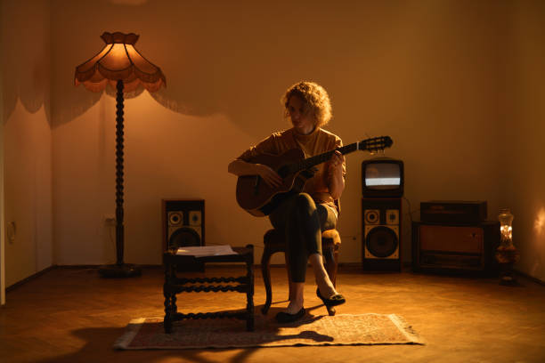 woman playing acoustic guitar in a retro vintage room. - fingerstyle imagens e fotografias de stock