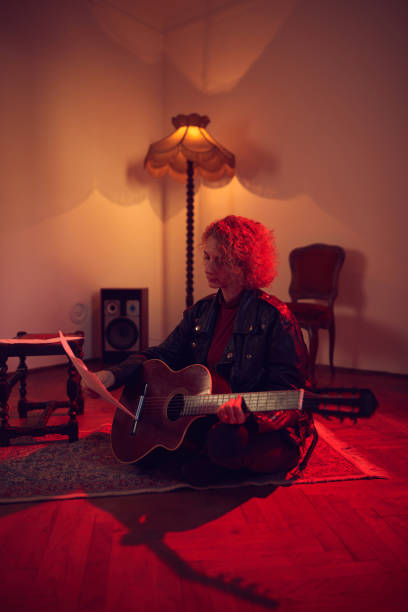 kobieta gra na gitarze akustycznej w retro vintage pokoju. - fingerstyle zdjęcia i obrazy z banku zdjęć
