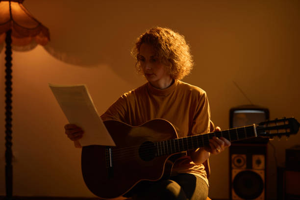 woman playing acoustic guitar in a retro vintage room. - fingerstyle imagens e fotografias de stock