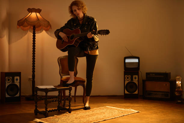 woman playing acoustic guitar in a retro vintage room. - fingerstyle imagens e fotografias de stock