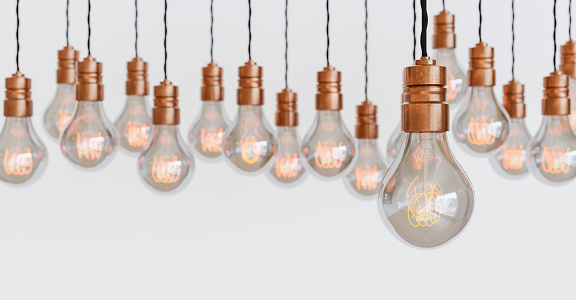 many vintage light bulbs hanging with copper bulb holders and orange filament. blurred background. white background. concept of electricity, energy. space for text. 3d render