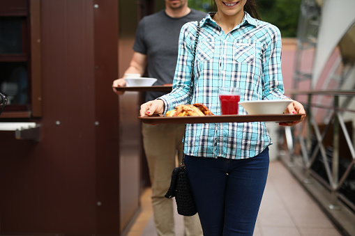 Woman and man are carrying food trays. Self-service and bbq system in restaurants and cafes concept