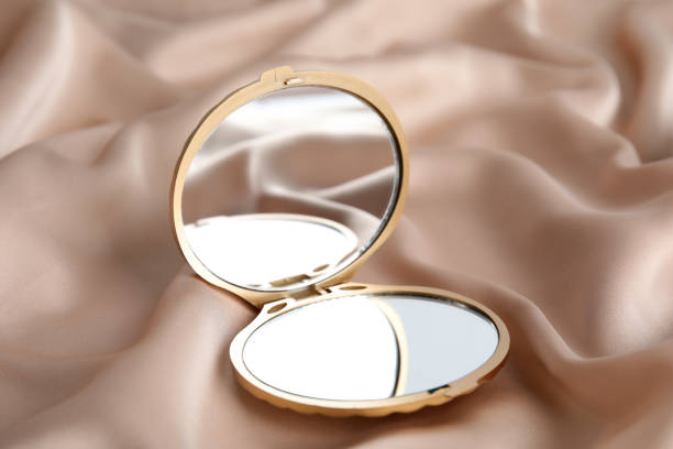 istock Bright cosmetic pocket mirror on rose gold fabric 1321100228