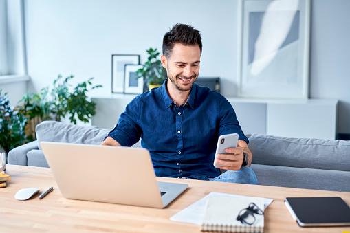 Young man working from home using mobile phone