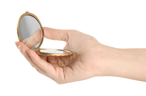 Woman holding gold cosmetic pocket mirror on white background, closeup