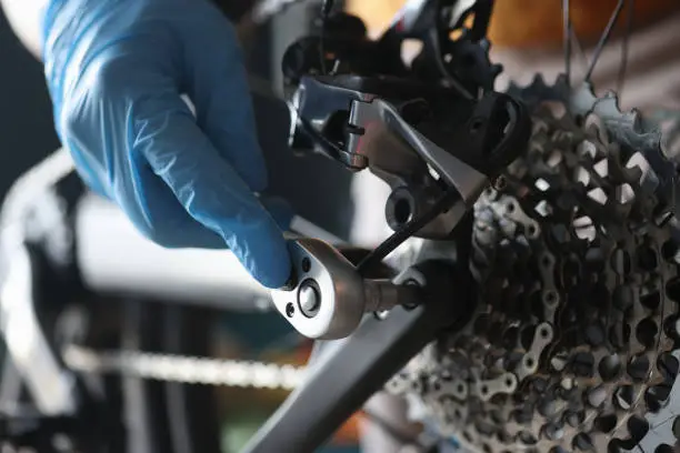 Gloved handyman repairs rear cassette of sports bike. Maintenance and repair of bicycles