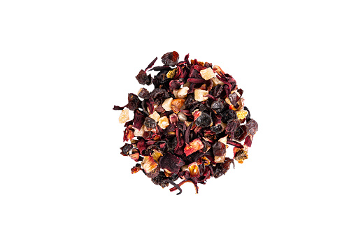Fruit tea leaves with candied fruits and dried fruits on a white background. A pile of fruit tea in a circle shape. View from above.