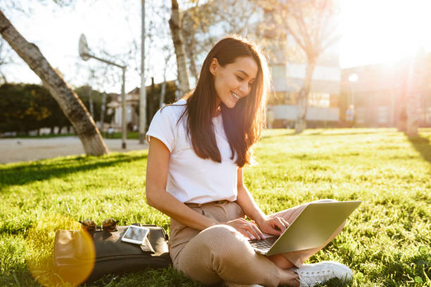 istock Gorgeous beautiful woman sitting on grass using laptop computer 1321103587