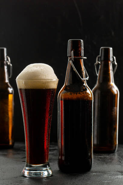 istock Dark crafted beer in glass and bottle on black background 1321107131