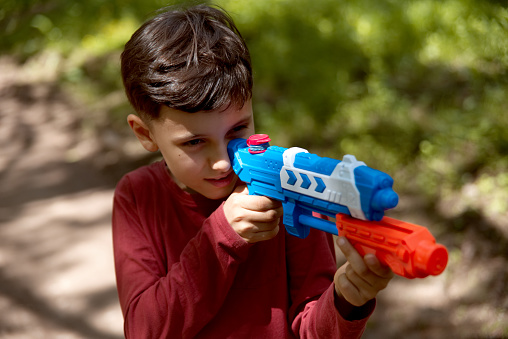 Portrait of young boy playing with water gun.