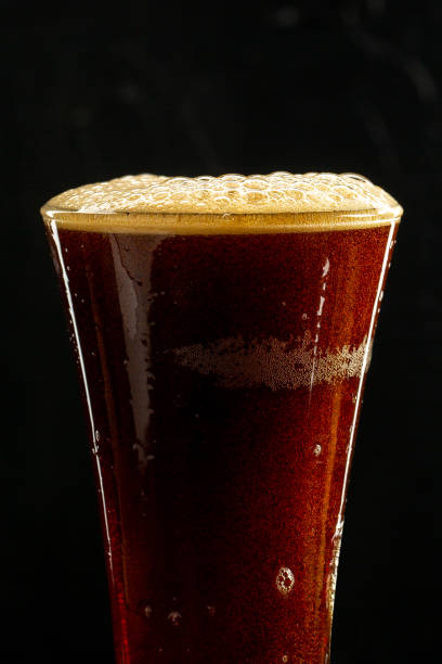 istock Dark crafted beer in glass and bottle on black background 1321107399