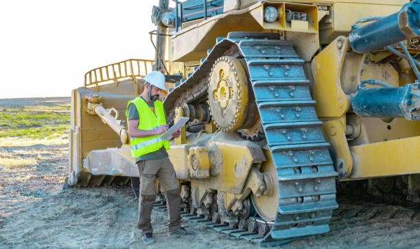 gestionnaire d’entretien prenant des notes sur une inspection d’une machine de fabrication de routes lourdes, bulldozer, gros tracteur de construction - trop lourd photos et images de collection