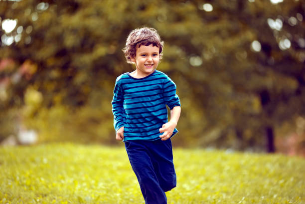 istock Cute boy running across grass und smiling. 1321109362
